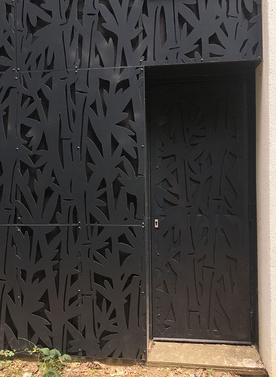 Habillage de porte en tôle décorative au motif végétal découpé laser.